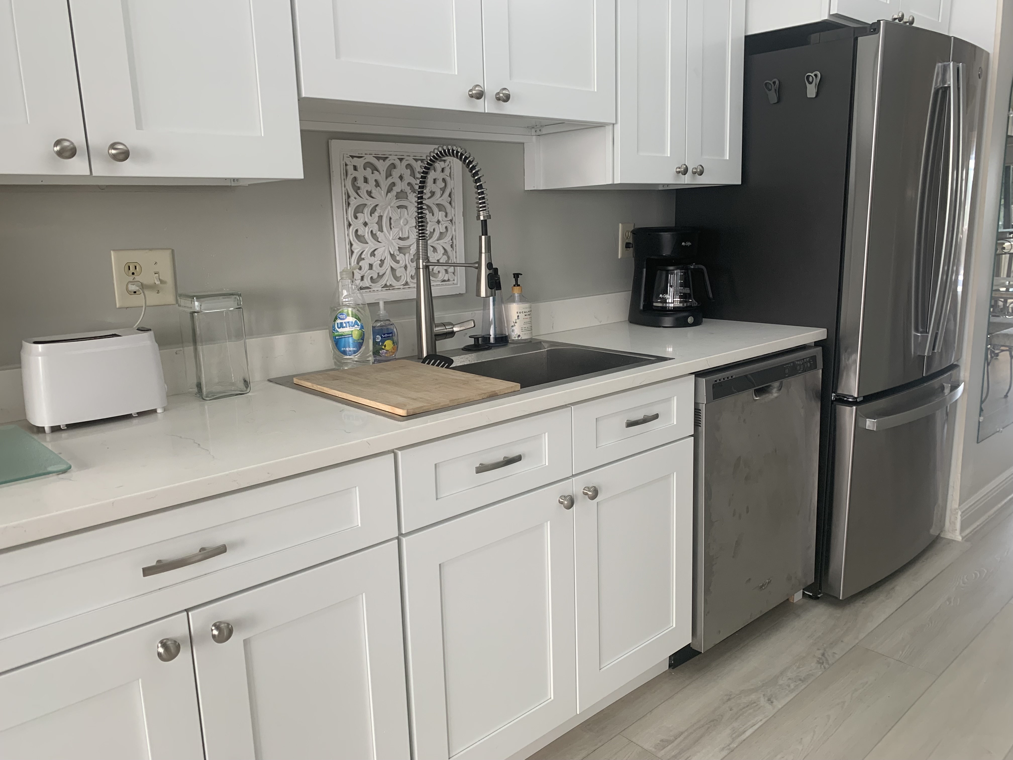 Updated kitchen with white cabinets, quartz counters, and stainless fridge